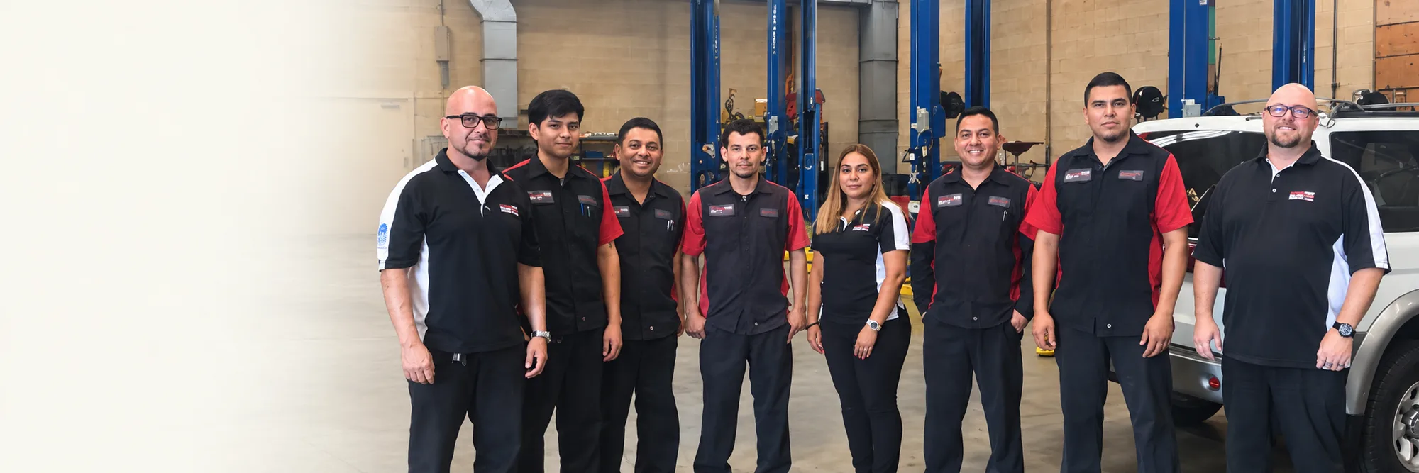 The eight-person LA Auto Center team standing together in the service bay