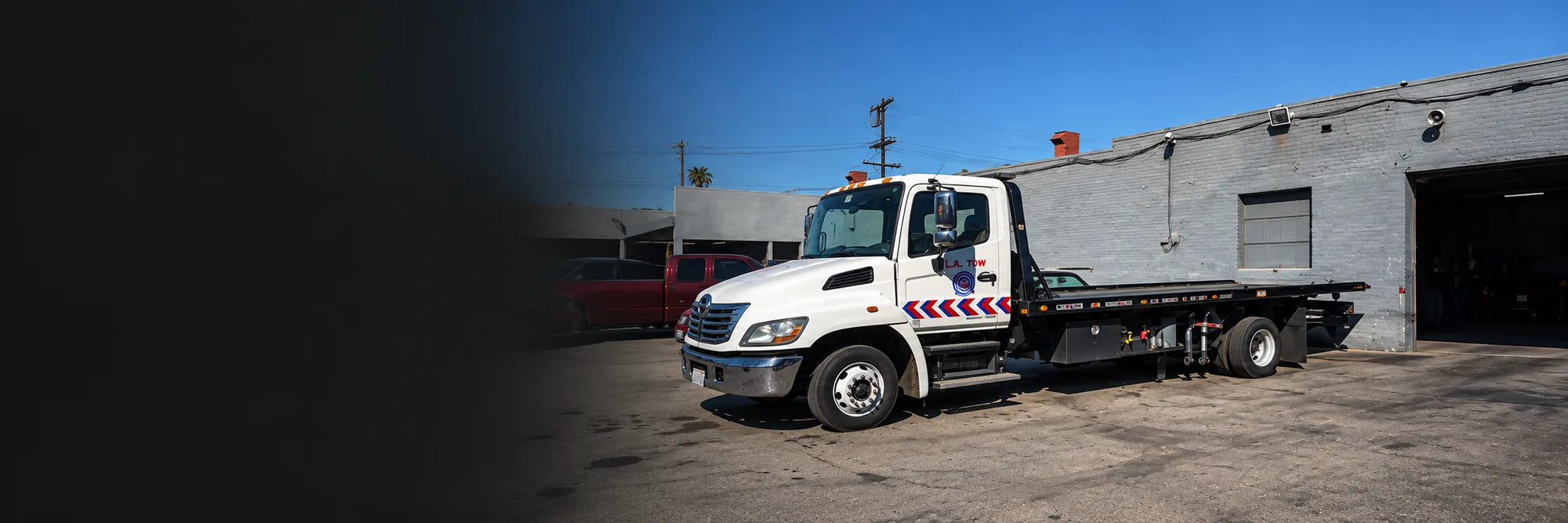 White flatbed tow truck parked outside the shop